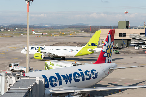 Zurich, Switzerland, January 19, 2023 Air Baltic Bombardier CS-300 and an Edelweiss Airbus A320-214 aircraft at the gate