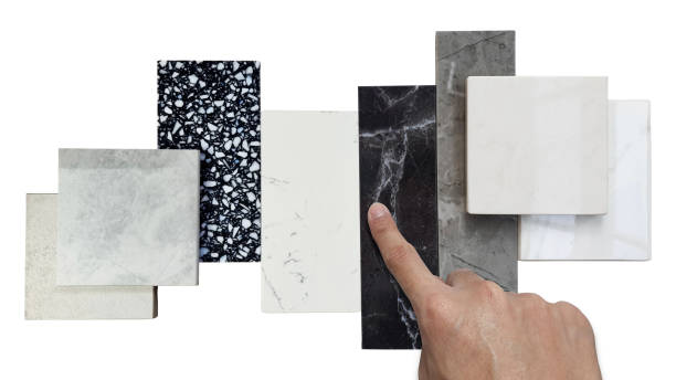 istock close up designer's hand picking interior premium stone samples including black marble, grey artificial stone, terrazzo tiles placed with floor tiles isolated on background with clipping path. 1471221387