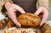 Close-up of male hands holding freshly baked bread on wooden table
