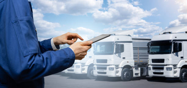 istock Manager with a digital tablet on the background of trucks. 1471225628