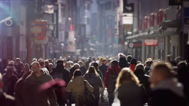 A crowd of people on a bright winter day on an urban high street in Europe, anonymous faces