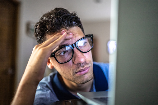 Worried young man working using laptop at home