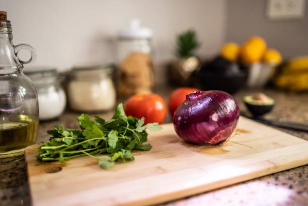 Coriander, onion on a cutting board at the kitchen counter at home