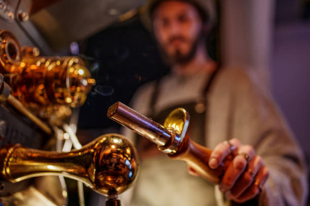Male coffee shop employee using a coffee bean roasting machine and checking the coffee beans.