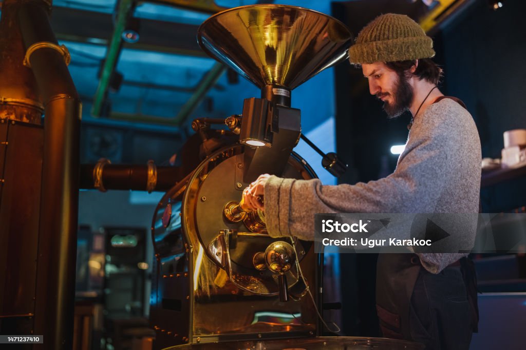Male Barista Roasting the Raw Coffee Beans. Coffee Roaster Stock Photo
