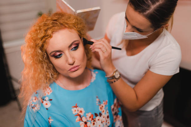 istock Beautiful blonde with curly hair getting her makeup done 1471239903