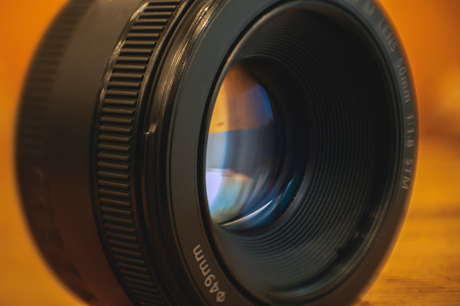 Detail shot of a 50mm photographic reflex camera lens on an orange background