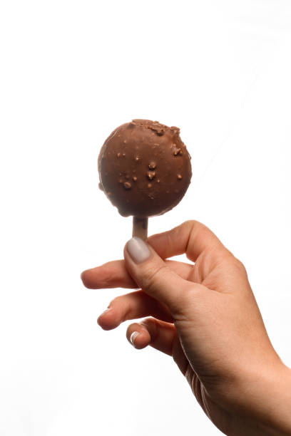 istock sweet macaron covered with chocolate icing on stick in female hand 1471246644