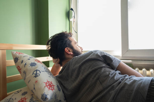 istock alone handsome man lying on his bed and looking out the window 1471247884