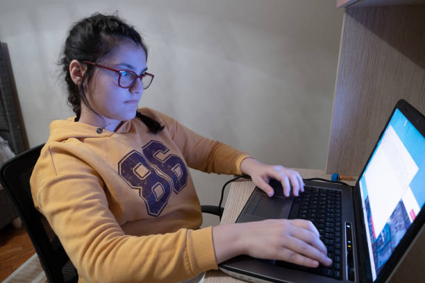 ragazza di 12 anni che digita nel suo computer nella sua stanza - child student adolescence cute foto e immagini stock