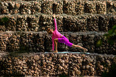 woman doing yoga against the backdrop of rocky steps. . Parivrtta utthita ashwa sanchalanasana
