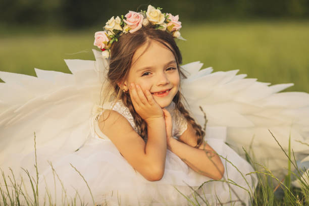 Angel with white wings on green grass. Blonde girl in dress on summer background Angel with white wings on green grass. Blonde girl in dress on summer background flower girl stock pictures, royalty-free photos & images