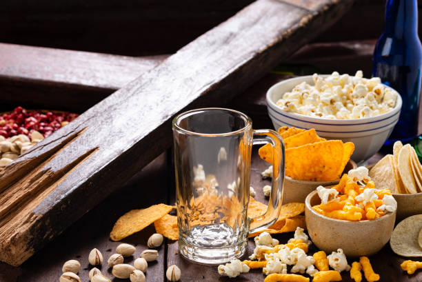 Studio shot of empty glass of beer with appetizers as popcorn, potato chips,  pistachio,  popcorn ,peanuts and nachos chips with cheese.