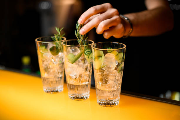 istock Selective focus on glasses with gin tonic cocktail which hand of bartender decorate with rosemary branch 1471254593