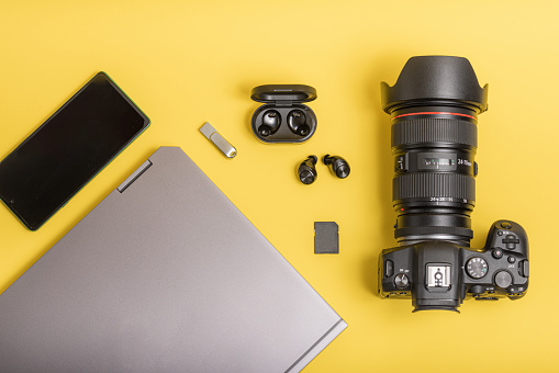 Workspace with camera, laptop, mobile phone, headphones on yellow background. Flat lay photographer equipment