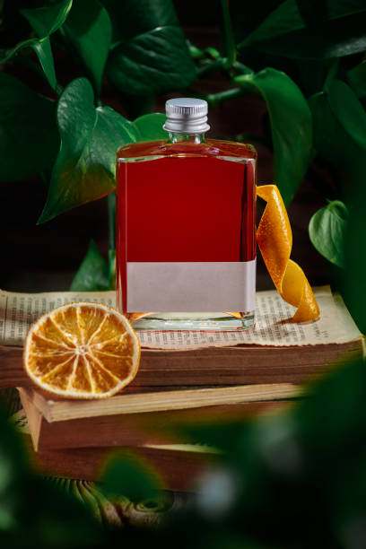 glass jar with red liquid of alcohol, drink prepared with orange peel and dried fruit on books and plant environment glass jar with red liquid of alcohol, drink prepared with orange peel and dried fruit on books and plant environment, clouse up sketch restaurant stock pictures, royalty-free photos & images