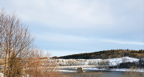 Winter landscape of bridge and River.  Homes in background. Month of March.