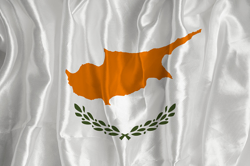 The flag of Cyprus on a silk background is a great national symbol. Fabric texture The official state symbol of the country.