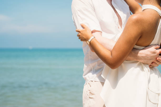 Young couple in love outdoor. Happy man Hugging and laughing to his woman romantic at tropical beach. Girlfriend with boyfriend resting travel at sunrise in summer.