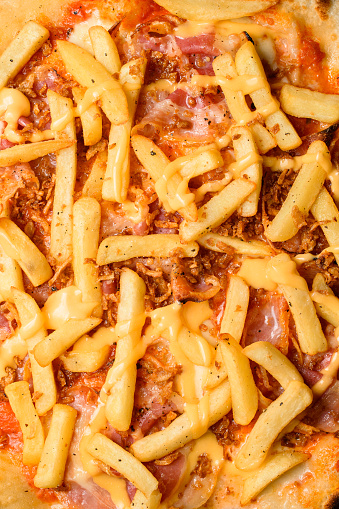 Close-up top view on pizza topping of tasty pizza with french fries and bacon slices
