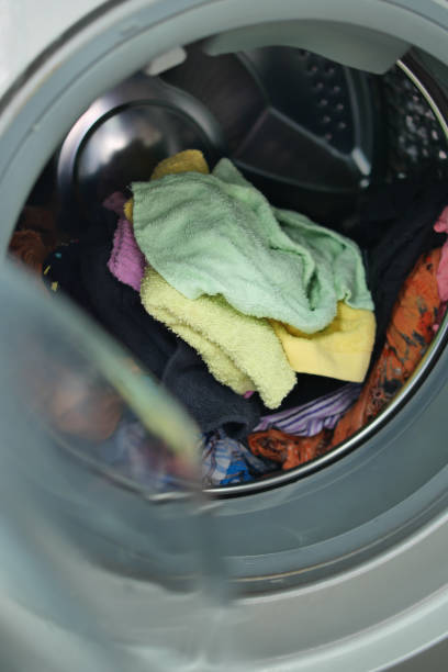 istock man putting shirt into washing machine. 1471272353