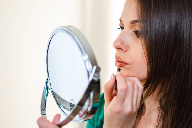 istock Beautiful woman applying lipliner while holding a mirror 1471277886