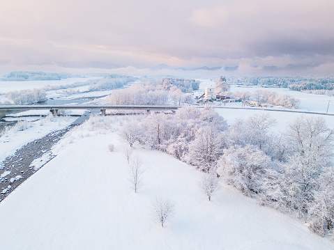 A drone point of view at sunrise over a snowy rural Japan landscape.