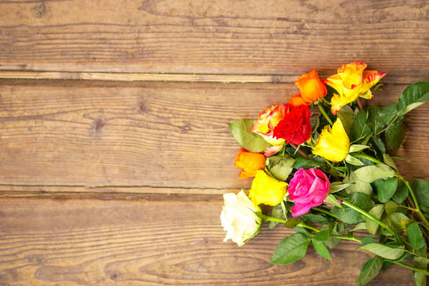 Colorful rose flowers bouquet on the vintage brown wooden background. Top view with copy space. Mothers or womens day greeting card. High quality photo.