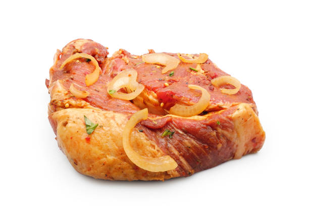 Raw pork loin steak marinated with onion, parsley and spices for bbq grill isolated on white background