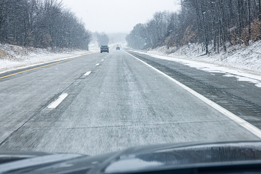 Car driver's point of view speeding on a remote stretch of a multiple lane highway expressway during a Northeastern United States winter snow storm.