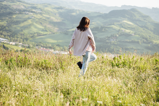 A young girl with a backpack climbs a mountain. Beautifull cloudy sky. Leisure. Hiking. Hoverla Mountain. Ukraine. Healthy lifestyle.