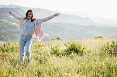 happy female dancing in a sunset meadow in mountains.