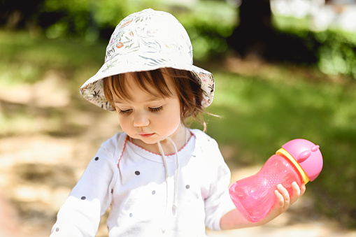 cute baby girl holding a bottle with water.