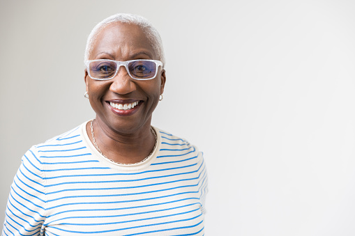 Studio portrait of a mature black woman in a stripped t-shirt and white glasses