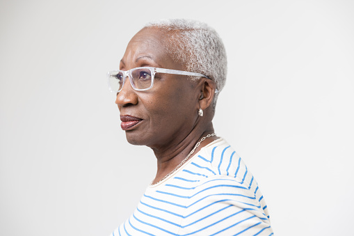 Studio portrait of a mature black woman in a stripped t-shirt and white glasses