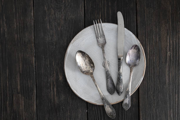 istock Vintage silver cutlery set on white plate on wooden background 1471298637