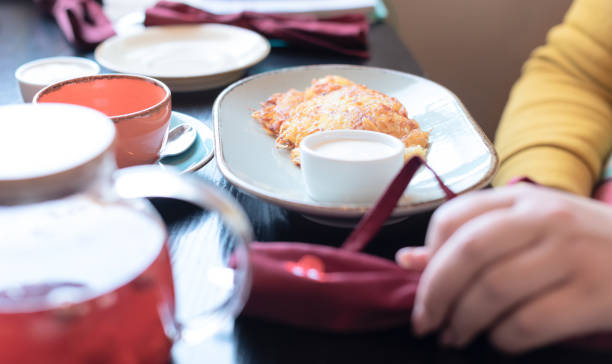 Plus size body positive woman dressed in yellow having breakfast at the cafe early in the morning with selective focus