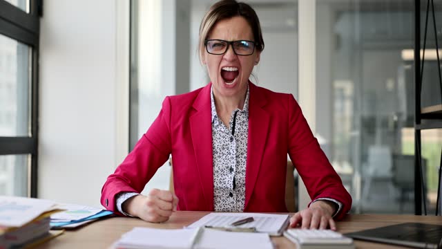 Angry female boss in office points to knock on table with your fist