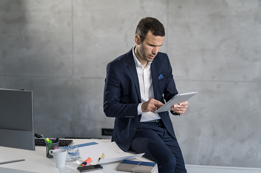 Mid adult engineer analyzing new work projects on digital tablet in the office.