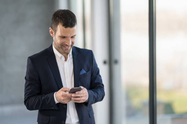 istock Happy businessman checking e-mails on phone in the office. 1471317861