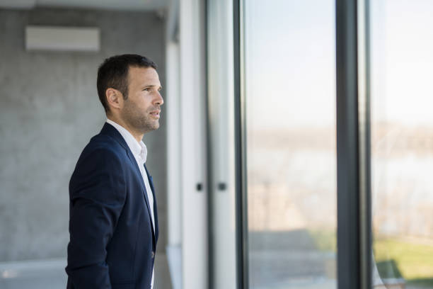 istock Pensive businessman looking through window. 1471320408