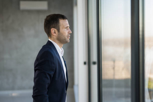 istock Pensive businessman looking through window. 1471320590