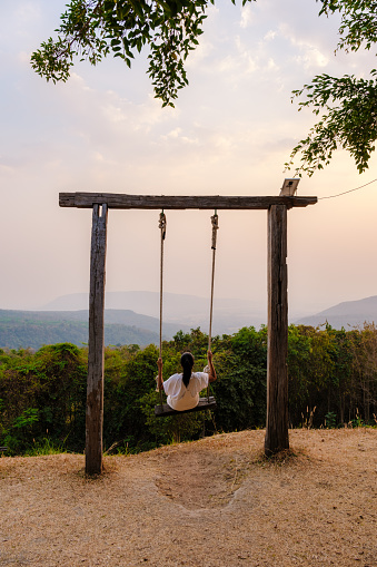 Asian women in a swing at Sunset at a mountain camping in Phitsanulok Thailand. luxury glamping