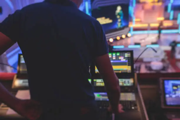View of a lighting technician operator working on mixing console workplace during live event concert on stage show broadcast, light mixer controller panel, sound technician with professional equipment