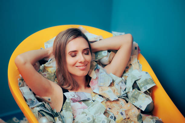 Rich Carefree Woman Bathing in a Tub of Money stock photo