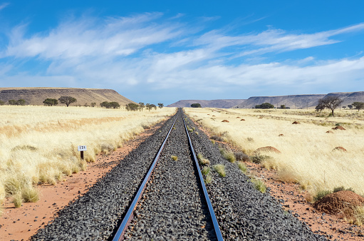 Railway in african savannah landscape, railroad in savanna grassland with mountains on background, Namibia, South Africa