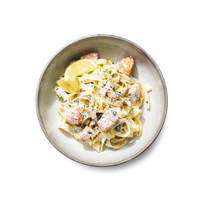 Italian made fettuccine pasta with creamy sauce and grilled salmon. top view, isolated on white background