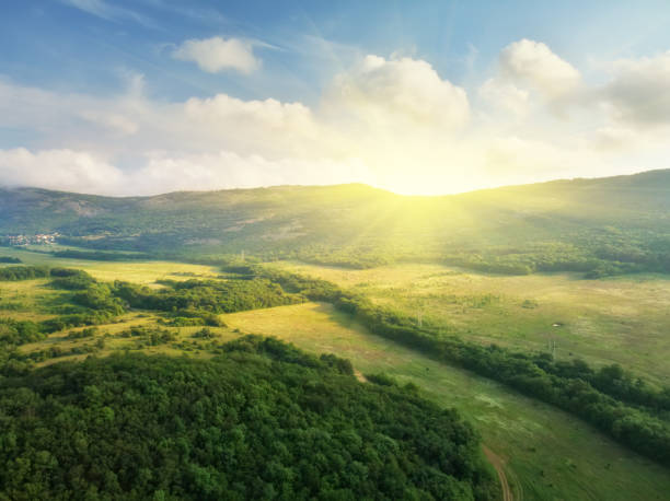Scenic aerial view of beautiful landscape Scenic aerial view of beautiful landscape of the valley and hills in the background and dramatic clouds in the sky. sun above clouds stock pictures, royalty-free photos & images