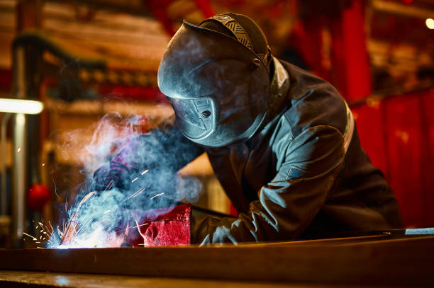 istock Laborer in protective mask welds manually metal frame 1471355491
