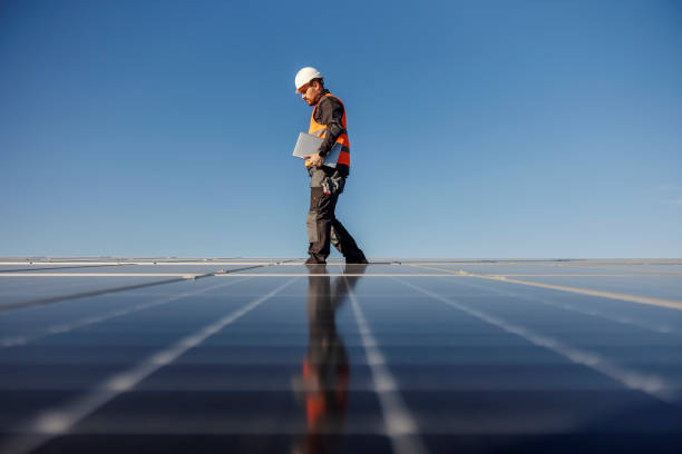 istock A supervisor is walking on the rooftop with solar panels and holding tablet under armpit. 1471358286